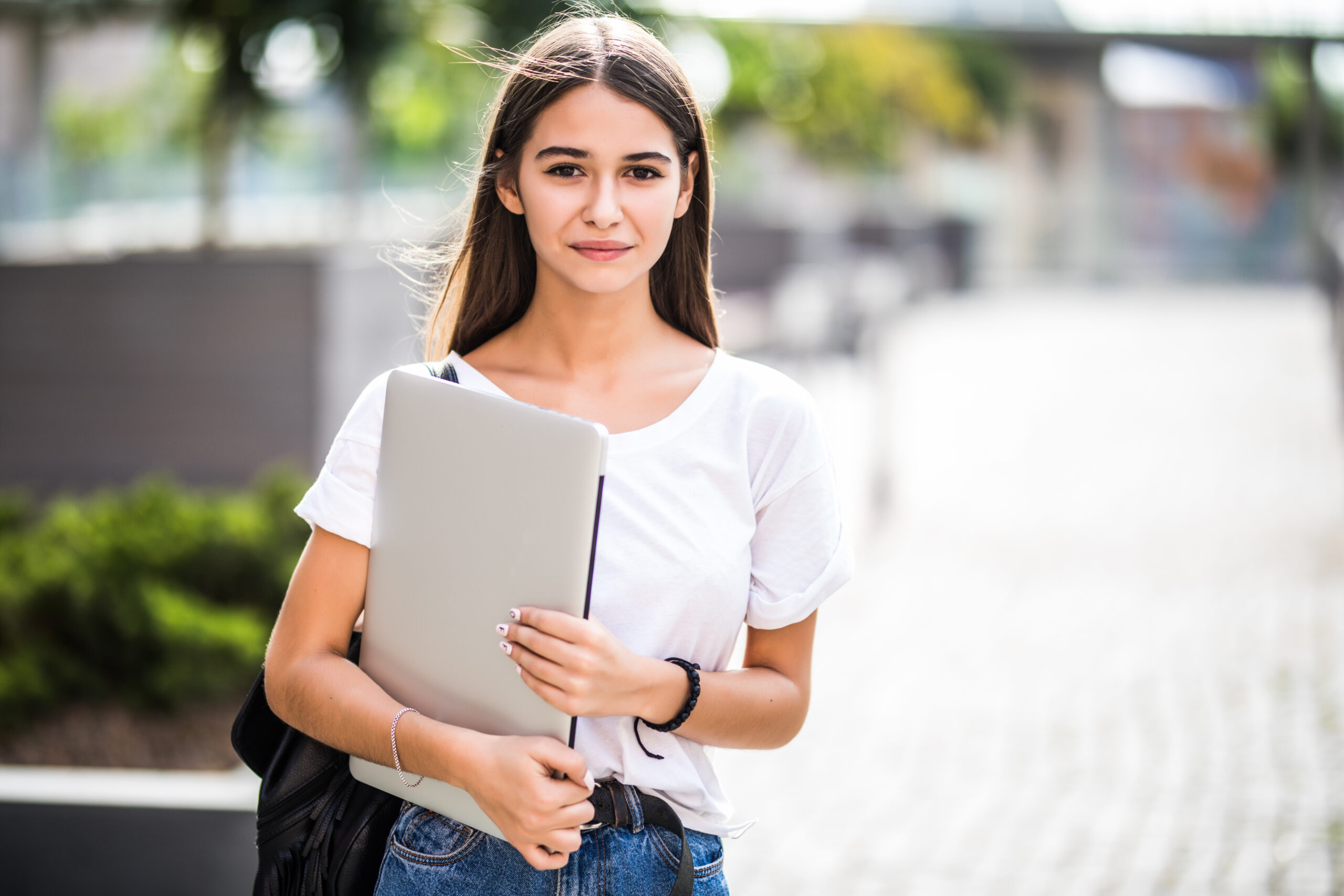 Portrait of young happy blogger with modern laptop near stone wall